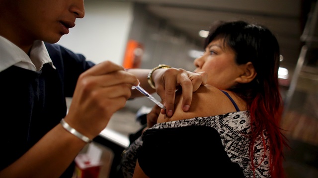 A woman receives a flu vaccination by injection for seasonal flu