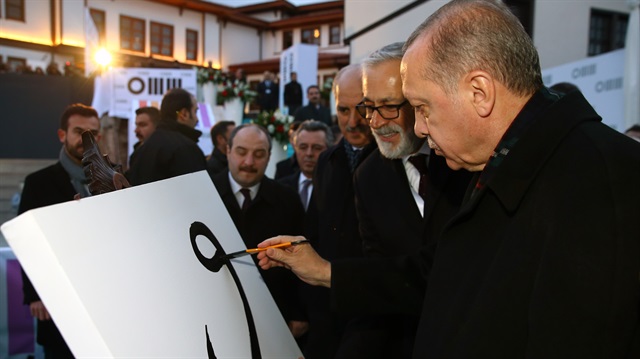 Cumhurbaşkanı Erdoğan,  kendisi için hazırlanan boş tuvale, Arapça'daki "Vav" harfini hat sanatına uygun şekilde çizdi.  