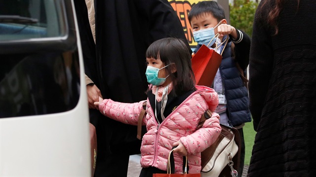 Kindergarten students wearing masks to ward off flu get on a school bus