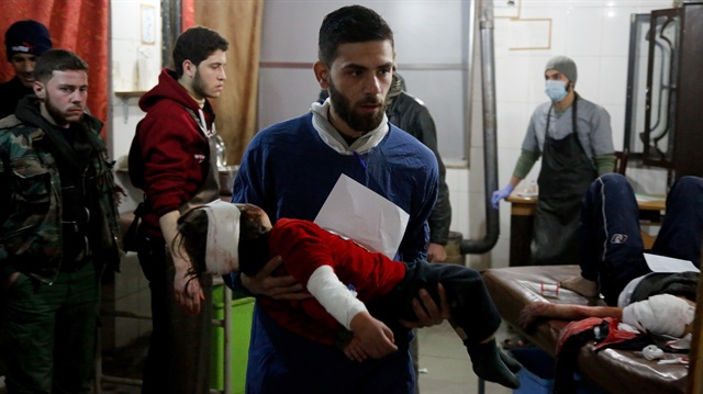 A Syrian man carries a wounded kid at a field hospital after war planes belonging to Assad Regime carried out airstrikes at the residential areas of Kafr Batna town which is a de-escalation zone of the Eastern Ghouta region of Damascus in Syria on February 18, 2018.