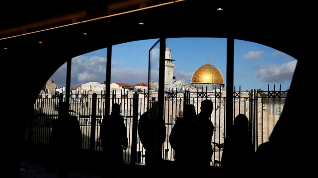 People look out from a building facing the Dome of the Rock