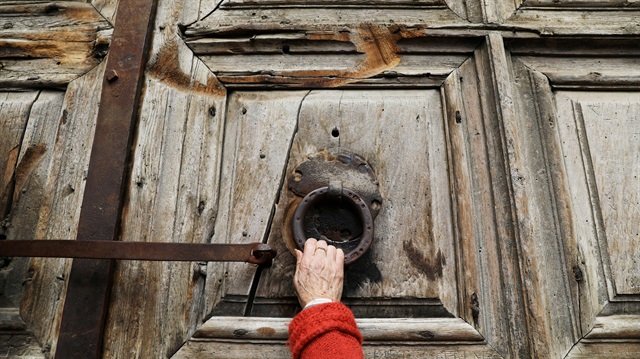 A worshipper touches the closed doors of the Church of the Holy Sepulchre in Jerusalem's Old City