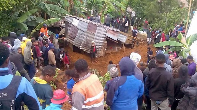 Locals surround a house that was covered by a landslide in the town of Mendi after an earthquake struck Papua New Guinea's Southern Highlands.