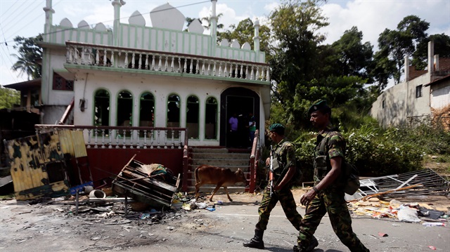 Sri Lanka's Special Task Force soldiers walk past a damaged mosque