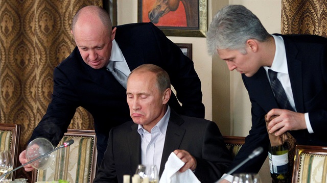 Evgeny Prigozhin (L) assists Russian Prime Minister Vladimir Putin during a dinner with foreign scholars and journalists at the restaurant Cheval Blanc on the premises of an equestrian complex outside Moscow November 11, 2011. 
