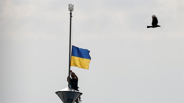 A climber installs the Ukrainian national flag on a roof, marking the Day of the State Flag, on the eve of the Independence Day, in Kiev, Ukraine, August 23, 2016.