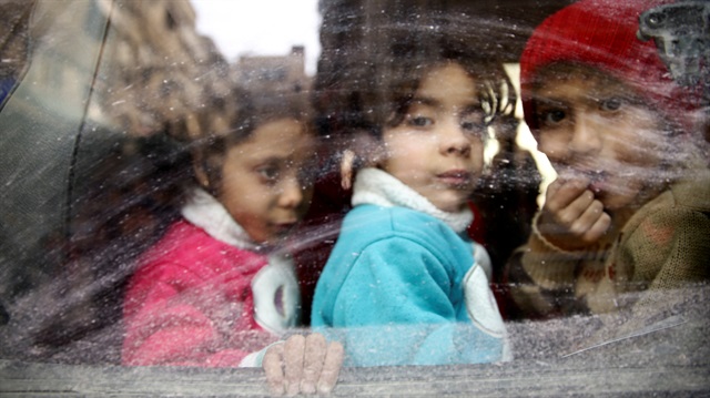 Children look through a bus window during evacuation from the besieged town of Douma, Eastern Ghouta, in Damascus, Syria.