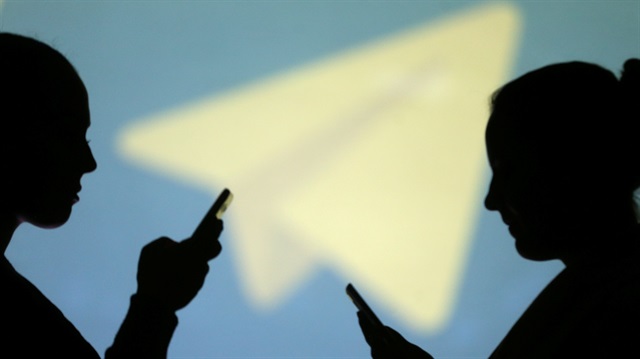 Silhouettes of mobile users are seen next to a screen projection of Telegram logo in this picture illustration taken March 28, 2018. 