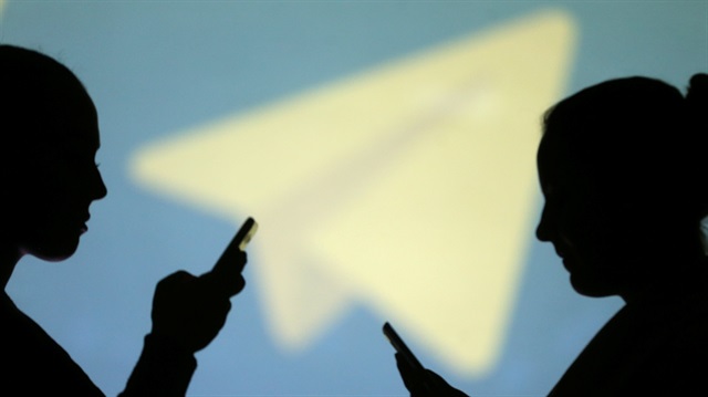 Silhouettes of mobile users are seen next to a screen projection of Telegram logo in this picture illustration taken March 28, 2018.
