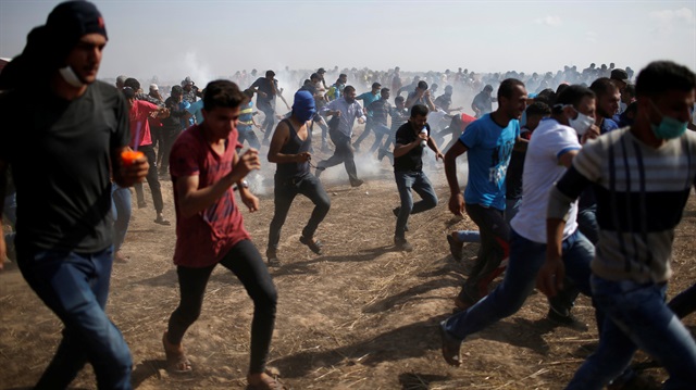 Palestinian demonstrators run for cover from tear gas fired by Israeli forces during a protest demanding the right to return to their homeland, at the Israel-Gaza border, east of Gaza City May 11, 2018.