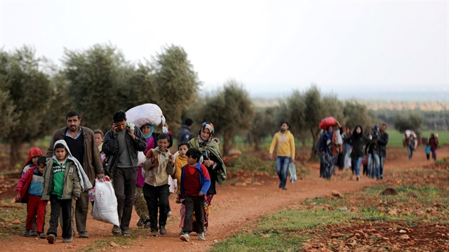 Internally displaced people walk with their belongings