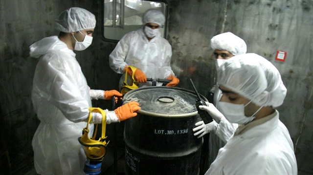 Iranian technicians lift a barrel of "yellow cake" to feed it into the processing line of Uranium 