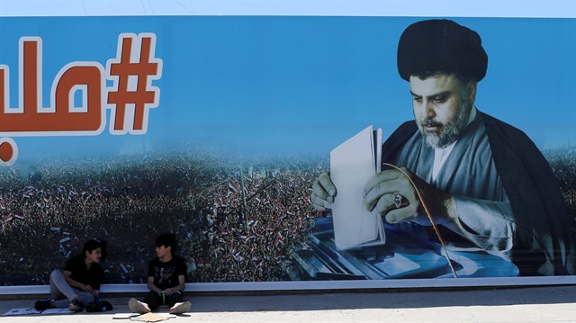 Boys sit next a poster of Iraqi Shi'ite cleric Moqtada al-Sadr in the Sadr City district