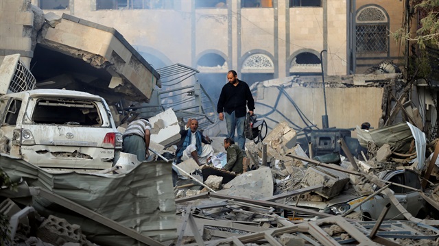 Guards search the wreckage of a building one day after air strikes destroyed it in Sanaa