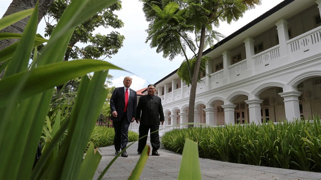 File Photo: U.S. President Trump and North Korea's Kim walk together before their working lunch during their summit in Singapore