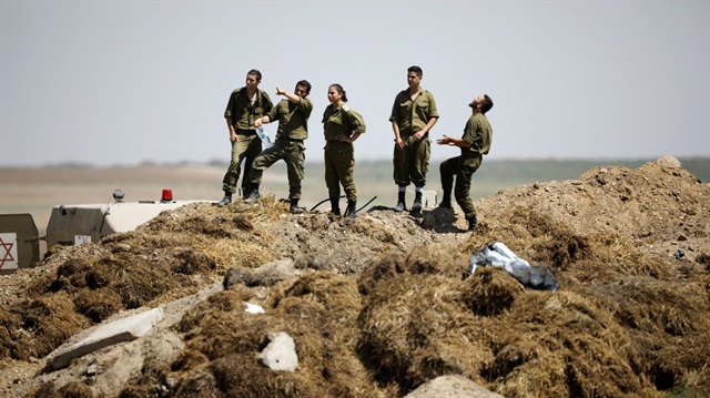 Israeli soldiers look over to the fence from the Israeli side of the border between Israel and Gaza 