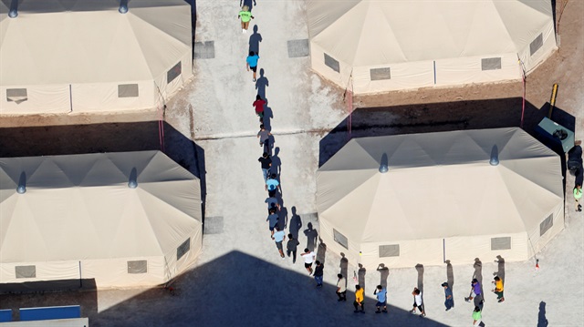 Immigrant children, many of whom have been separated from their parents under a new "zero tolerance" policy by the Trump administration, walk in single file between tents in their compound next to the Mexican border in Tornillo, Texas, U.S. June 18, 2018. 