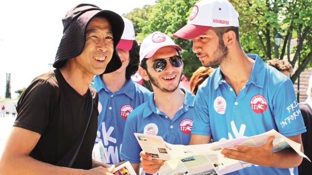 "Ask Me (Bana Sor)" yazılı tişörtler giyen "Gönüllü Turizm Elçileri" turistlere yardımcı oluyor.