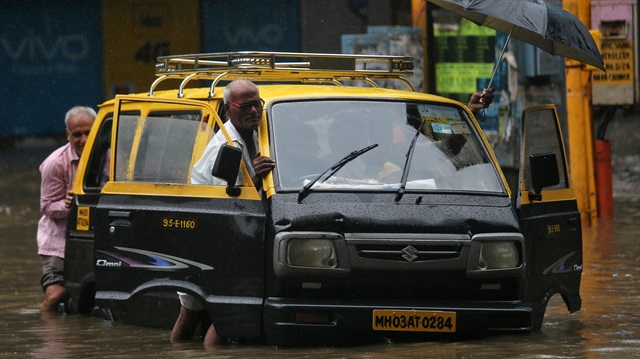 People push a taxi through a waterlogged street after heavy rains in Mumbai, India.