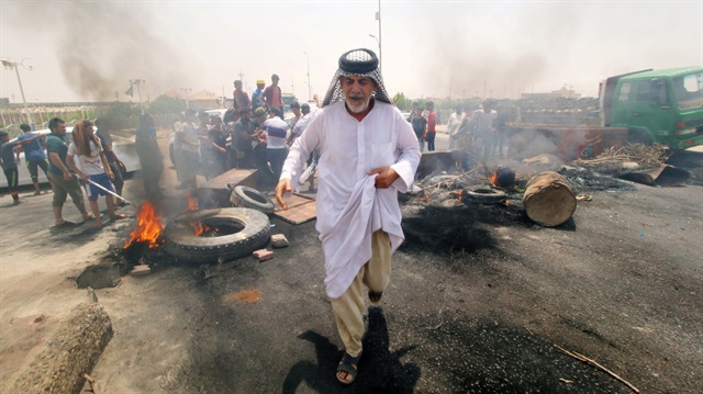 Iraqi protesters burn tires and block the road at the entrance to the city of Basra