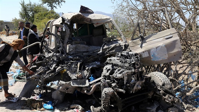 Pro-government fighters inspect a Houthi vehicle destroyed in an air strike