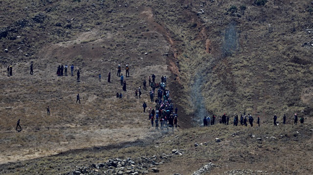 People walk towards the border fence between Israel and Syria from its Syrian side as it is seen from the Israeli-occupied Golan Heights near the Israeli Syrian border