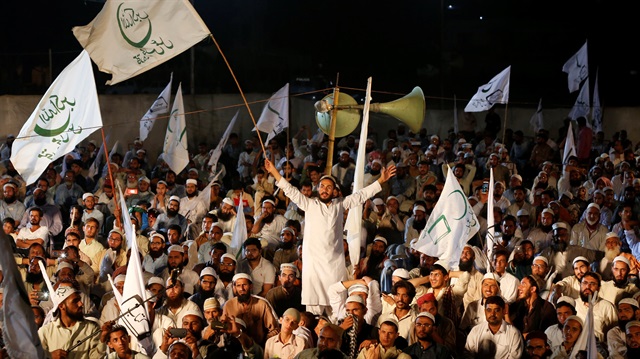 A supporter of the Muttahida Majlis-e-Amal (MMA), a coalition between religious-political parties, chant slogans and waves a flag with others, during a campaign rally, ahead of general elections in Karachi, Pakistan.