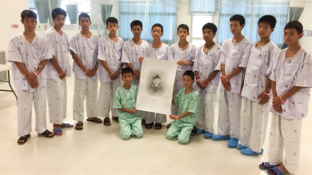 The 12-member "Wild Boars" soccer team and their coach rescued from a flooded cave pose with a drawing picture of Samarn Kunan, a former Thai navy diver who died working to rescue them at the Chiang Rai Prachanukroh Hospital, in Chiang Rai, Thailand July 14, 2018. 