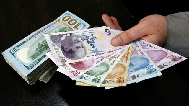 A money changer holds Turkish lira banknotes next to U.S. dollar bills at a currency exchange office in central Istanbul, Turkey.