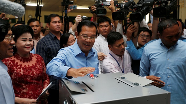 Cambodia's Prime Minister and President of the Cambodian People's Party (CPP) Hun Sen casts his vote as his wife Bun Rany stands beside him at a polling station during a general election in Takhmao