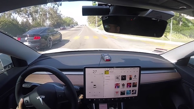 Ford Mustang GT'ye kafa tutan Model 3'ün sürücü koltuğundan bir kare.