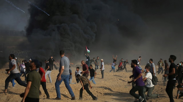Tear gas canisters are fired by Israeli troops towards Palestinian demonstrators as they run during a protest demanding the right to return to their homeland at the Israel-Gaza border, in the southern Gaza Strip