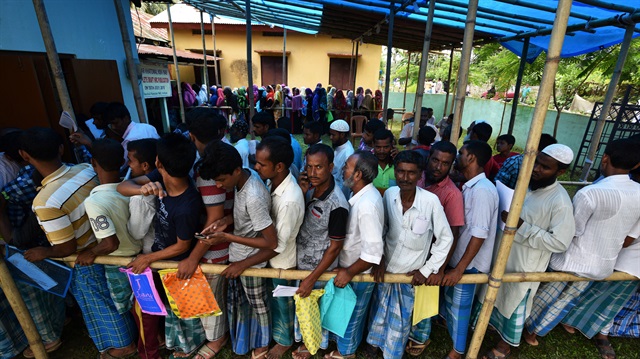 People wait in queue to check their names on the draft list at the National Register of Citizens