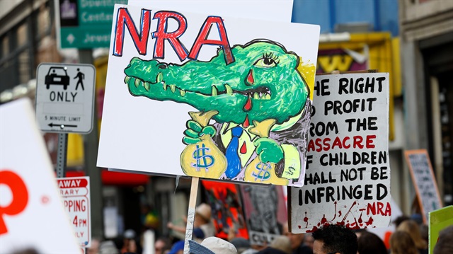 People walk with signs against the NRA during "March for Our Lives", an organized demonstration to end gun violence, in downtown Los Angeles, California, U.S.