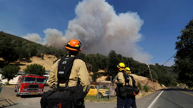 Firefighters on a structure protection team watch a plume of smoke grow from the Ranch Fire (Mendocino Complex) in the hills north of Upper Lake, California, U.S.