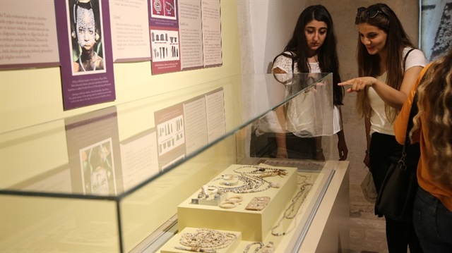 Biri kadın biri erkek iki yetişkinin üzerinden çıkan takılar Mardin Müzesinde boncuklu tarla vitrininde sergileniyor.