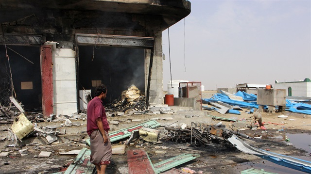A man stands at the scene of an airstrike that hit a truck at a petrol station in Abss, Yemen 