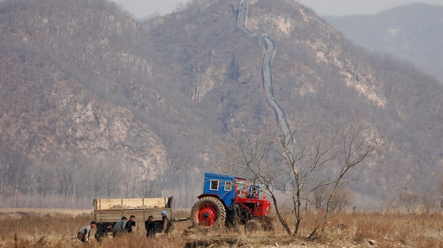File Photo: North Korean farmers work in a field as a section of the Great Wall is seen on the Chinese side of the Yalu River, north of the town of Sinuiju in North Korea and Dandong in China's Liaoning province.