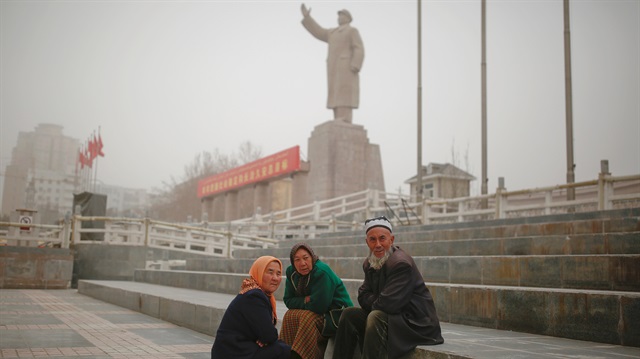 Ethnic Uighurs sit near a statue of China's late Chairman Mao Zedong in Kashgar, Xinjiang Uighur Autonomous Region, China.