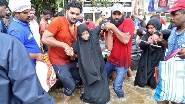 Rescuers help a woman to move through a water-logged road after she was evacuated