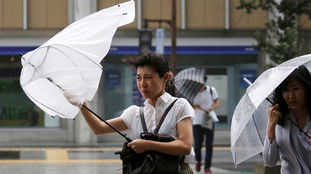File photo :Passersby using umbrellas struggle against a heavy rain in Japan's Tokyo