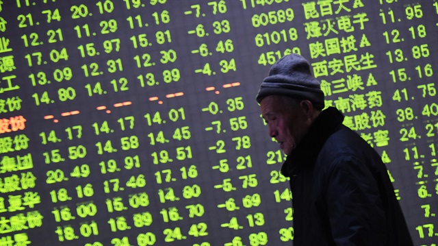 File photo: An investor walks past an electronic screen showing stock information at a brokerage house in China