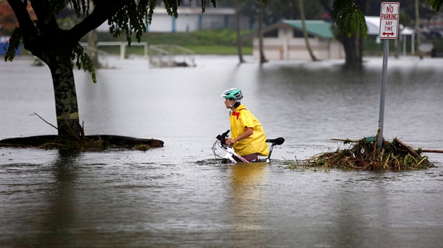 A woman pushes her bicycle through flooding caused by Hurricane Lane in Hilo, Hawaii