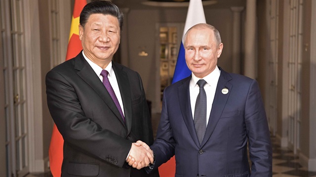 Russia's President Vladimir Putin (R) shakes hands with China's President Xi Jinping 