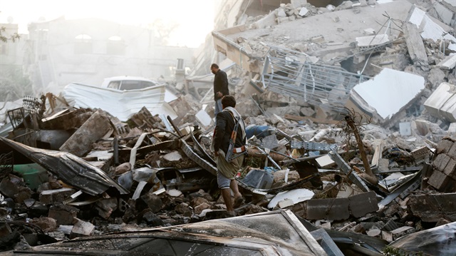 Guards walk on the wreckage of a building destroyed by air strikes in Sanaa, Yemen June 6, 2018. 