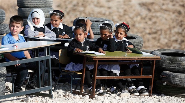 Filistinli öğrenciler, okul sıralarını dışarıya çıkararak açık havada ders yapıyorlar.