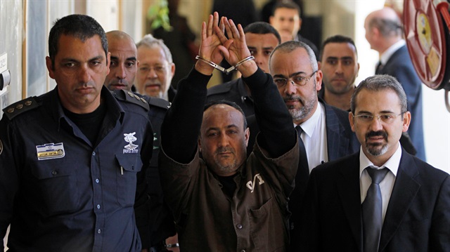 File photo: An Israeli prison guard escorts jailed Fatah leader Marwan Barghouti (C) to a deliberation at Jerusalem Magistrate's court January 25, 2012. 