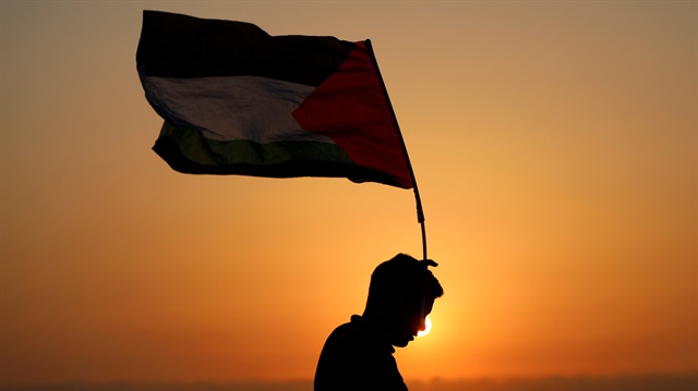 A demonstrator holds a Palestinian flag during a protest against Jewish settlements in the village of Ras Karkar, near Ramallah in the occupied West Bank August 30, 2018.