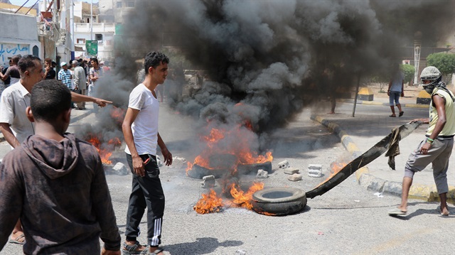 Protesters block a street with burning tires after the Yemeni Riyal has severely plunged