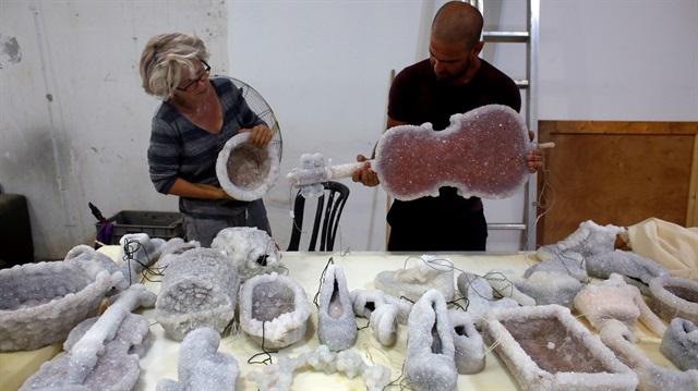 Israeli artist Sigalit Landau (L) and her partner Yotam, look at some of her art pieces, objects covered in salt crystal formations after they were removed from the hyper-saline waters of the Dead Sea, at Landau's studio in Kibbutz Almog, Israel August 30, 2018. 